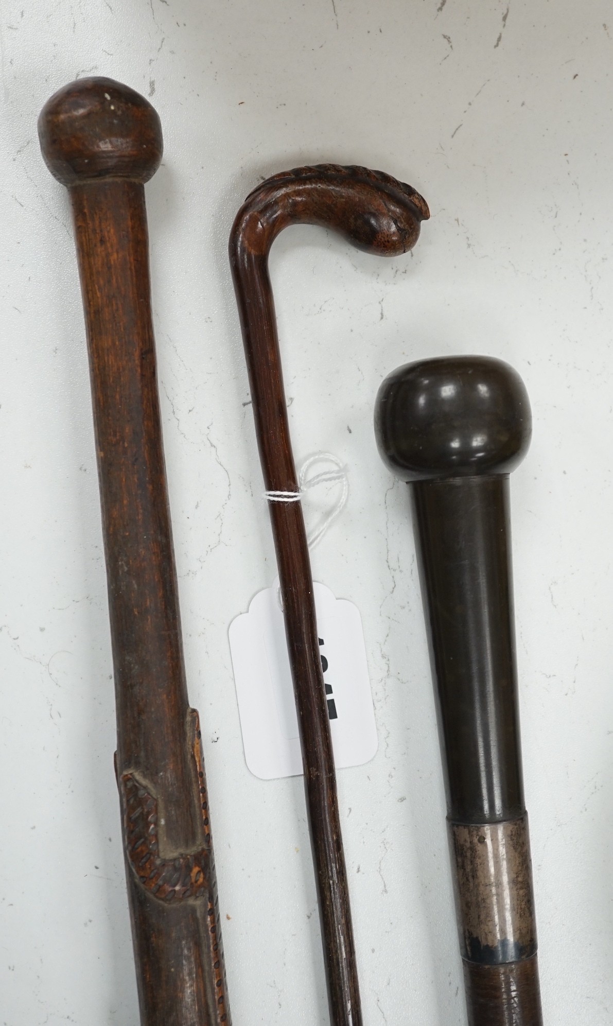 A bull's pizzle walking stick and two other carved wood sticks, largest 93cm